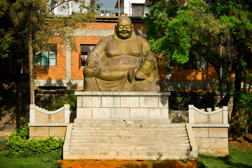 Asia, China, Yunnan Province, Mile. Bronze statue of a sitting Mile Buddha in city park.