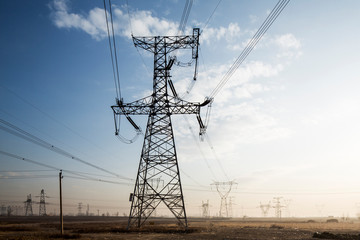 Fototapeta premium China, Shanxi Province, Datong, High Tension Power Pylons and electrical lines leading from coal-fired Datong No. 2 Power Station at dawn