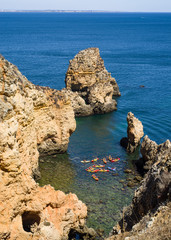 Vacation in Algarve - a group of tourists in kayaks seen from above  in a colourful bay  with cliffs of Ponta da Piedade. The rock formations and cliffs rising from the turquoise waters of the sea. 