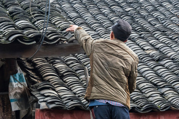 Fototapeta premium Repairing tiled roof of a traditional house, Pengzhen, Chengdu, Sichuan Province, China