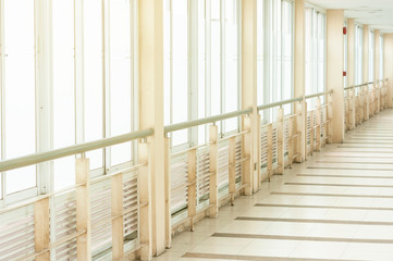 Fototapeta na wymiar Long corridor, walkway connection between building, empty walkway with windows and light flare.