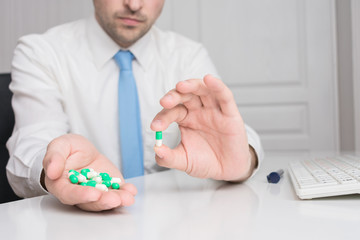 Man working in the office, shows a handful of capsules in his hand, close up