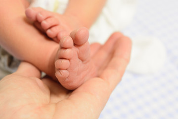 Obraz na płótnie Canvas Newborn baby feet in man hand with blue background