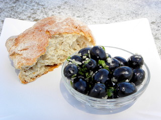 black olives in a glass bowl and a piece of bread