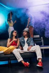 man with alcohol and girl sitting on couch in nightclub