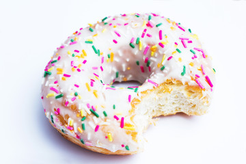 Bitten white donut with bright sprinkles, white background, close up, food concept