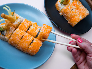 female hand takes Sushi roll with shrimp on a plate