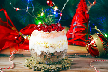 Festive layered salad serving in glass from smoked meat, egg, pomegranate seeds, carrot,onion, mayonnaise and cheese for New Year and Christmas