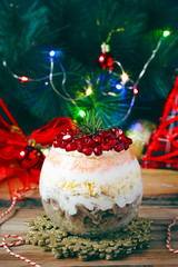 Festive layered salad serving in glass from smoked meat, egg, pomegranate seeds, carrot,onion, mayonnaise and cheese for New Year and Christmas