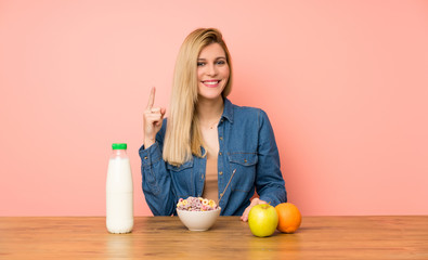 Young blonde woman with bowl of cereals pointing with the index finger a great idea