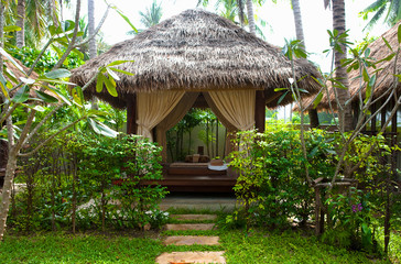 Fototapeta na wymiar Ko Samui, Thailand - Landscaped lawn with a walkway leading up to a small hut with canopy.