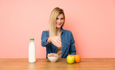 Young blonde woman with bowl of cereals handshaking after good deal