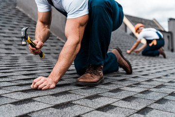 cropped view of repairmen in uniform working on rooftop © LIGHTFIELD STUDIOS