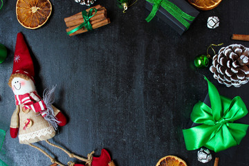 Christmas background with dry orange,white pinecone,green christmas tree balls,mandarins,red apple,ginger sticks,on a black background,flat lay,space for text,space for copy
