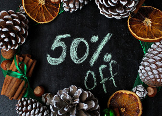 Christmas background with dry orange,white pinecone,green christmas tree balls,mandarins,red apple,ginger sticks,on a black background,flat lay,space for text,space for copy