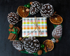 Christmas background with dry orange,white pinecone,green christmas tree balls,mandarins,red apple,ginger sticks,on a black background,flat lay,space for text,space for copy