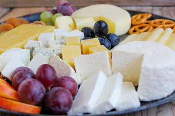 Rustic cheese platter with different cheese and grapes