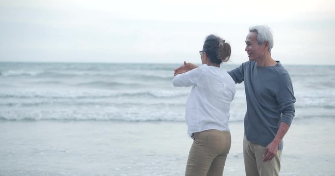 Romantic Asian Senior Couple Dancing On The Beach In Slow Motion.