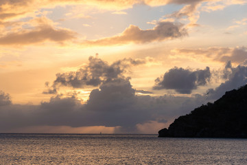 Obraz na płótnie Canvas UK, British Virgin Islands. Sailboat and rain on horizon at sunset