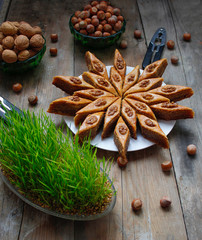 Traditional Azerbaijan holiday Nowruz cookies baklava on white plate on the rustic background with nuts and huzelnuts on green plate ,flat lay