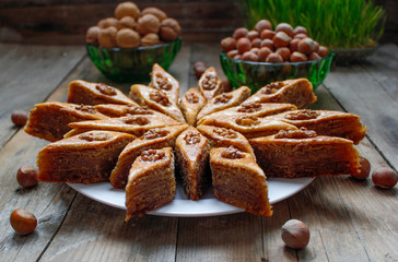 Traditional Azerbaijan holiday Nowruz cookies baklava on white plate on the rustic background with nuts and huzelnuts on green plate ,flat lay