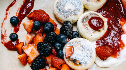 Homemade pancakes serving with fresh raspberry, blueberry, strawberry, with sauce and pondered sugar, selective focus, banner