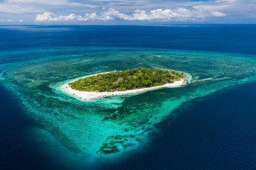Aerial drone view of a beautiful tropical island surrounded by coral reef (Mantigue Island, Camiguin, Philippines)