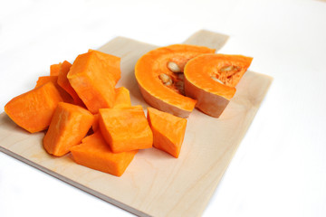 Two bowls of pumpkin soup on white background with gray fabric and slices of butternut squash,top view,vegetarian food