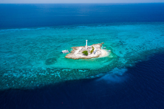 Aerial drone view of tropical Capitancillo Island in the Philippines showing its lighthouse and coral reef