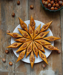 Traditional Azerbaijan holiday Nowruz cookies baklava on white plate on the rustic background with nuts and huzelnuts on green plate ,flat lay