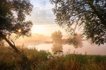 Foggy morning. Dawn outside the city. It will be a warm day. Morning fog on the lake