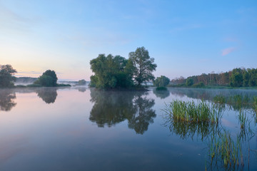 Fototapeta premium Foggy morning. Dawn outside the city. It will be a warm day. Morning fog on the lake