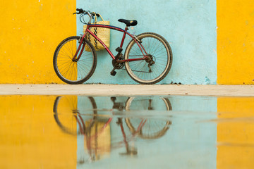 Cuba, Trinidad. Bicycle and reflection against yellow and blue walls.