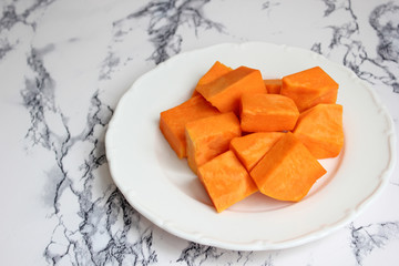 Two bowls of pumpkin soup on white background with gray fabric and slices of butternut squash,top view,vegetarian food