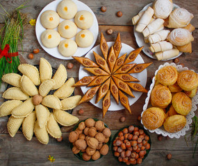 Traditional Azerbaijan holiday Nowruz cookies baklava on white plate on the rustic background with nuts and huzelnuts on green plate and shakarbura,gogal,sweetbread,flat lay