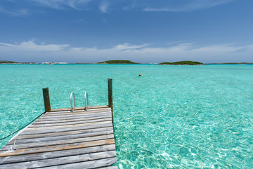 Dock in the foreground, clear water and blue sky in the background, taken on Staniel Cay, Exuma, Bahamas