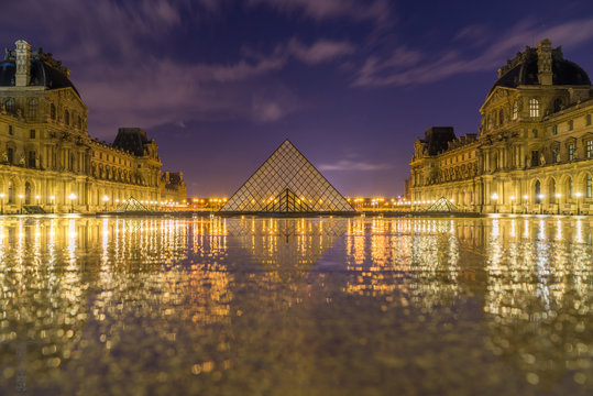 iew of famous Louvre Museum with Louvre Pyramid at evening