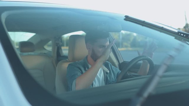 Confused young man driver beginner driving car for the first time. Portrait of inexperienced male learning how to drive to pass for license.
