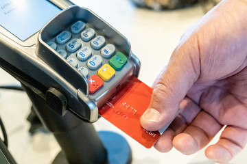 human hand holding a computer chip bae credit card while paying at a shop