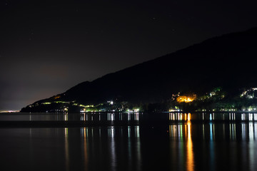 Night city in the reflection of the water of the sea. Night beach of pebbles Abkhazia Gagra. Black night, highlands, tourism, travel, night city.