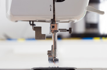 sewing machine with colour thread and needle on a table with blurred background, Tailor's work table, textile or fine cloth making, industrial fabric, home appliances tool.