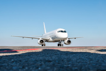 Taxiing a white passenger jet plane on the airport apron