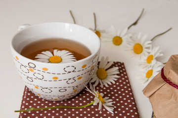 cup of tea on brown polka dot fabric with camomile on a white background