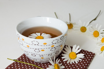 cup of tea on brown polka dot fabric with camomile on a white background
