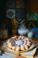 Twisted sweet bread canelbulle or cinnamon roll with chocolate and nuts on rustic background