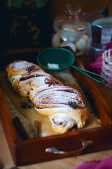 Twisted sweet bread canelbulle or cinnamon roll with chocolate and nuts on rustic background