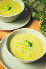 Fresh Broccoli cream soup on two gray ceramic bowl on plate with spoon on marble background,vegetarian food,healthy concept