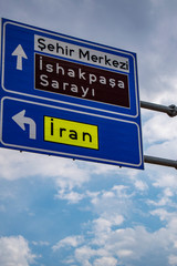 Dogubayazıt, Eastern Turkey, Middle East: the road sign to the Iran border and to the Ishak Pasha Palace, a semi-ruined palace and administrative complex of Ottoman period built from 1685 to 1784