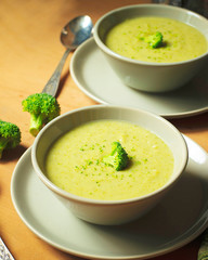 Fresh Broccoli cream soup on two gray ceramic bowl on plate with spoon on marble background,vegetarian food,healthy concept