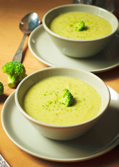Fresh Broccoli cream soup on two gray ceramic bowl on plate with spoon on marble background,vegetarian food,healthy concept